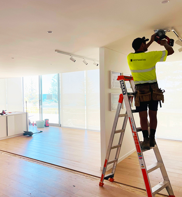 West Maintain workers stands on ladder to complete property maintenance services